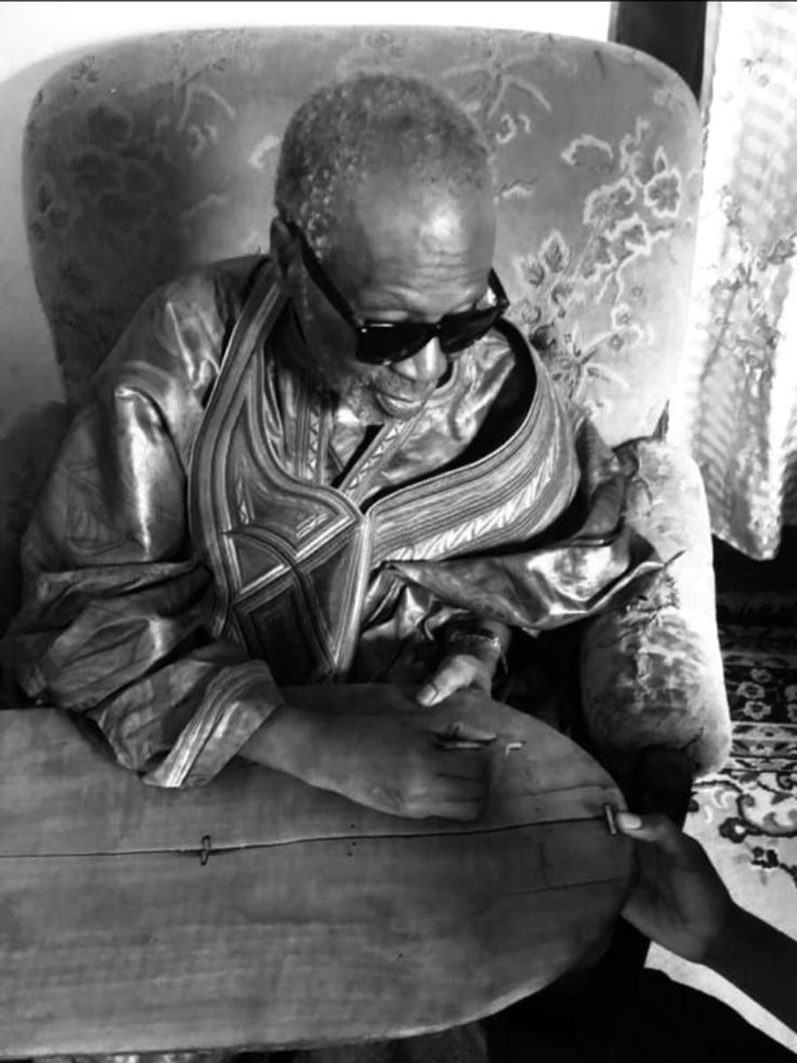 Le Marabout guérisseur Thierry, assis, traçant les signes d’un travail sur sa tablette de bois