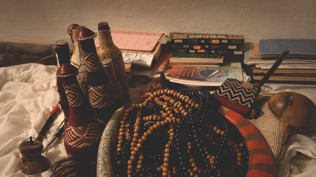Chapelets, flacons rituels et livres de travail posés sur une étoffe blanche